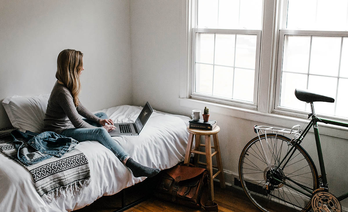 Woman sitting on a bed working on a laptop