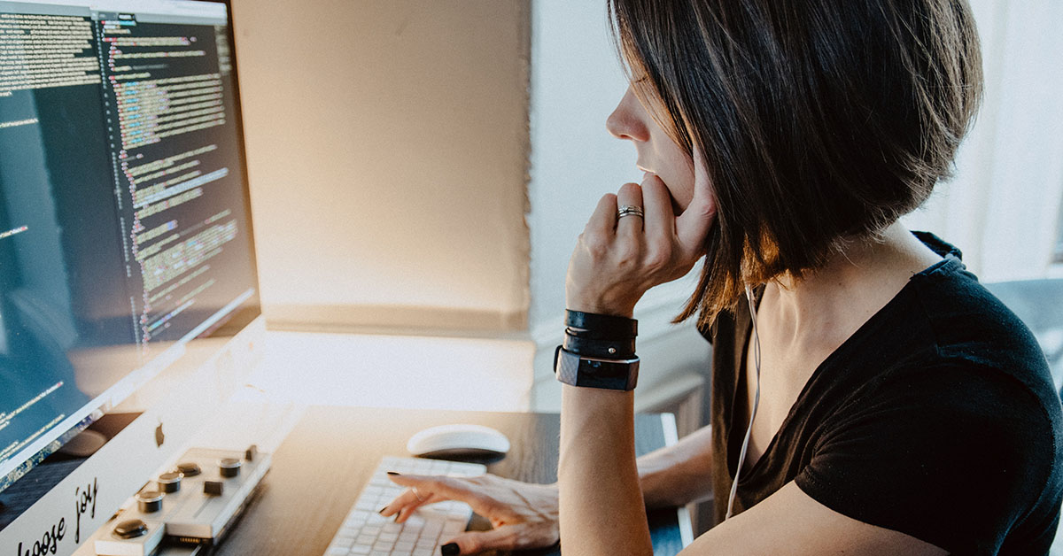 A woman in front of a pc looking at code