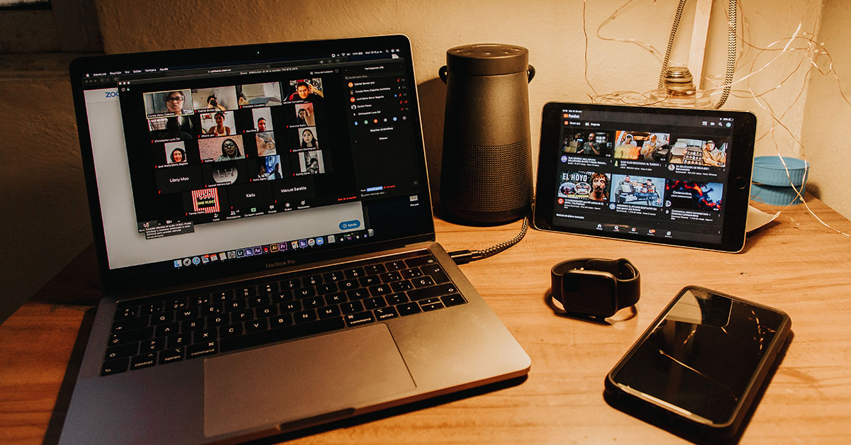 An laptop and tablet on a table with open communication windows for conference calls