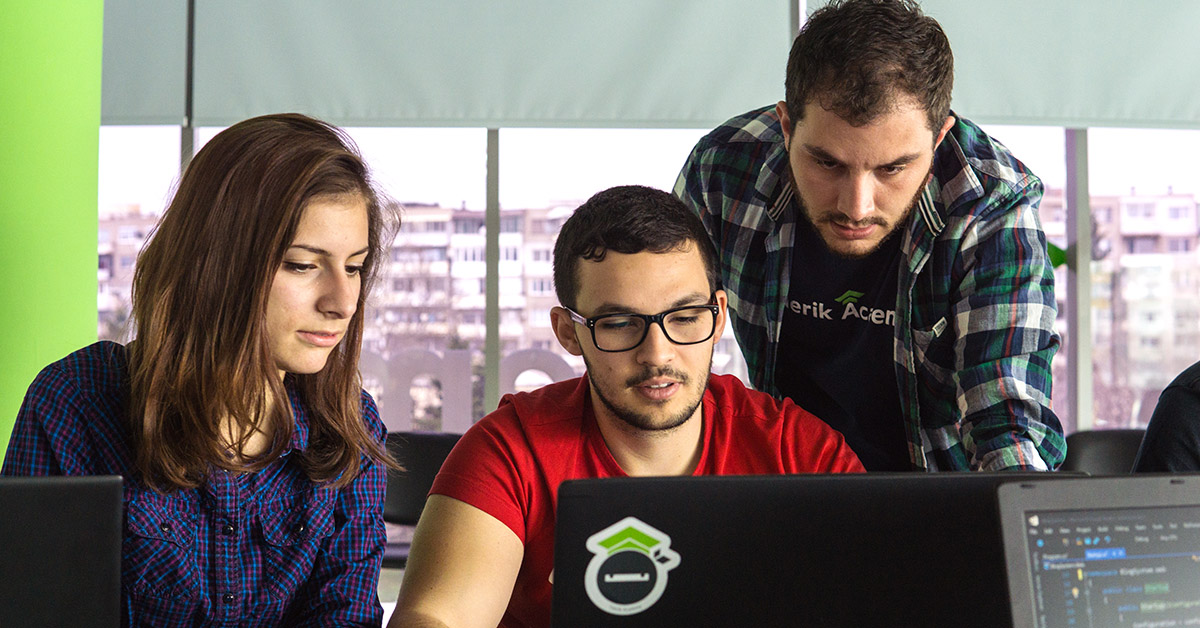 Two boys and a girl in front of a computer learning to code at telerik academy 