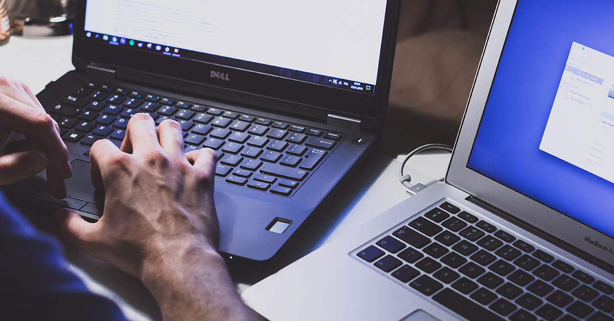 photo of someone using two laptops - one with windows and one with macos